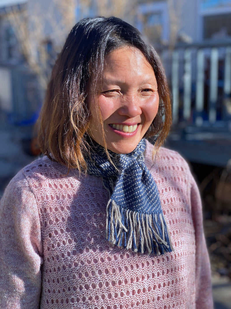 Wendy wearing the a blue and gray scarflet wrapped around the neck and tied loosely at the neck.