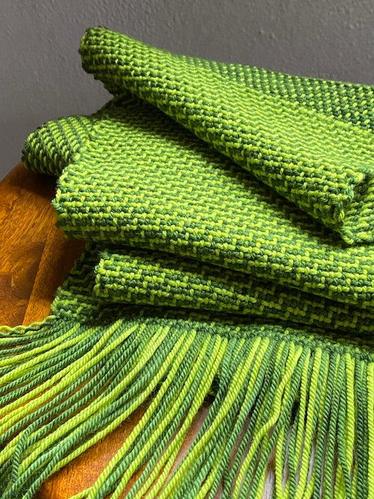 Green color-and-weave twill scarf draped on a stool. 