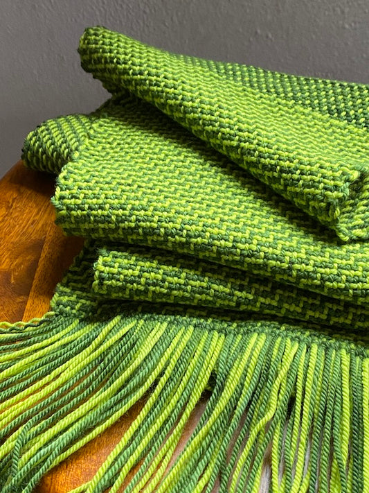 Green color-and-weave twill scarf draped on a stool.